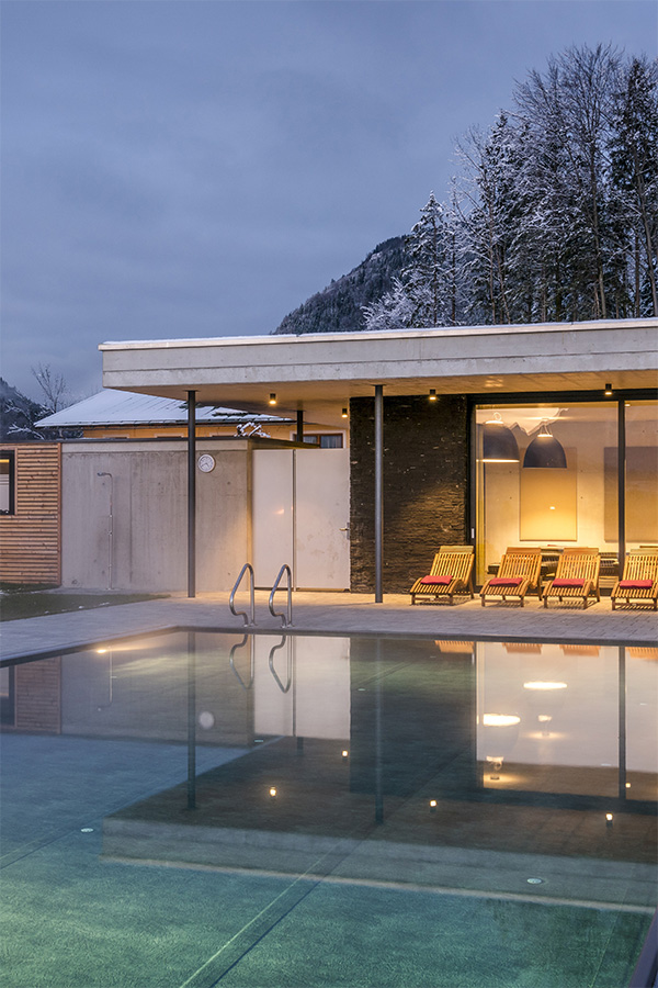 Beleuchteter Pool und Wellnessgebäude in der Dämmerung
