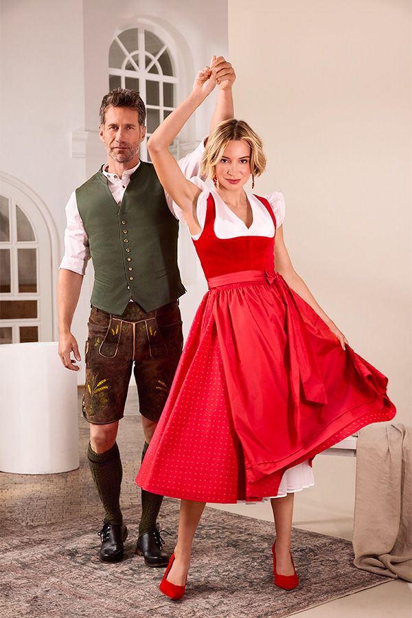 Paar in Tracht, sie im roten Dirndl, er in grüner Weste und Lederhose