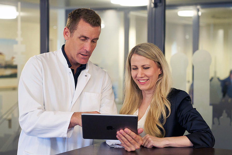 Arzt und Frau schauen gemeinsam auf ein Tablet