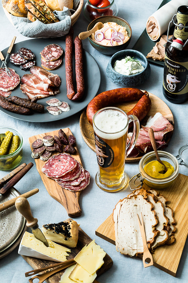 Gedeckter Tisch mit Wurstwaren, Käse und Bier