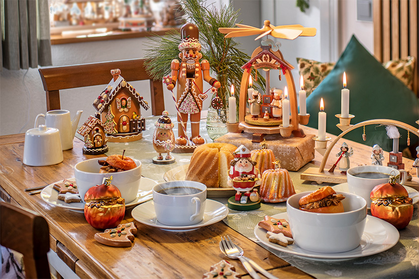 Gedeckter Tisch mit Lebkuchenhaus, Weihnachtspyramide und Gebäck
