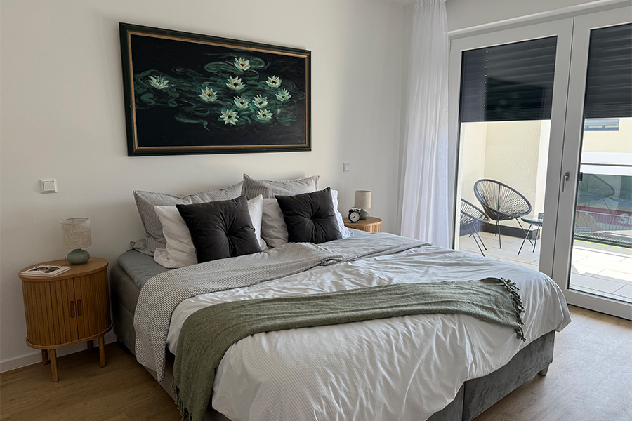 Helles Schlafzimmer mit Doppelbett und Balkontür