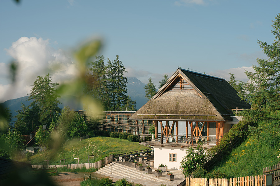 Haus mit Strohdach zwischen Bäumen im Sommer