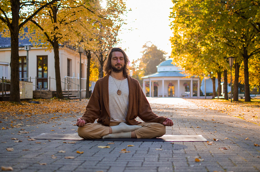 Mann meditiert auf einem herbstlichen Platz